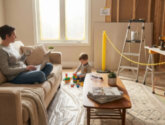 Homeowner watching remodel work in living room, dust and tools, living in house during renovations